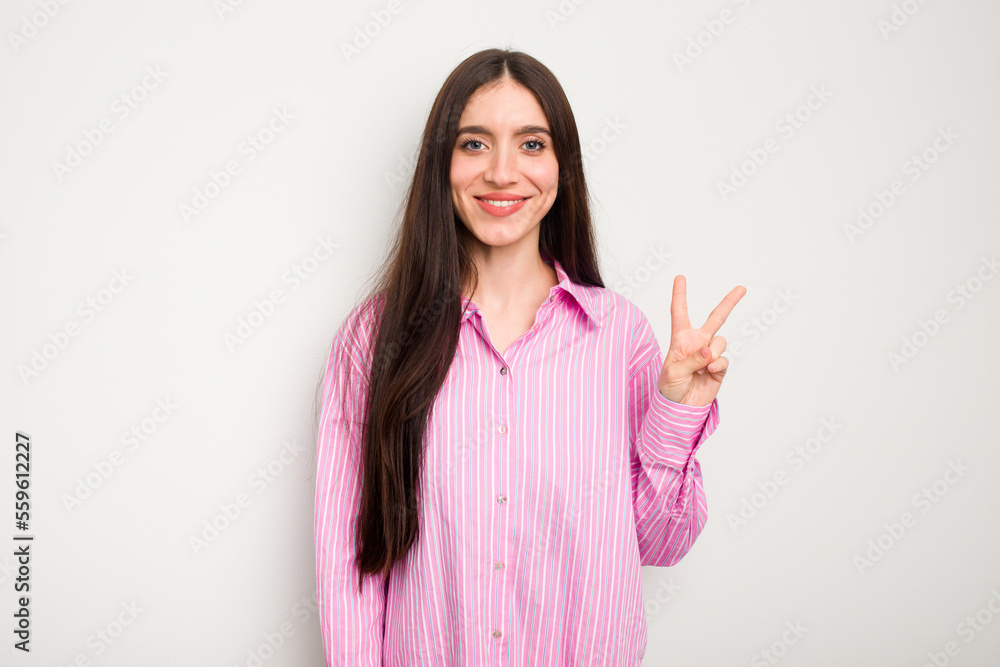 Young caucasian woman isolated on white background showing victory sign and smiling broadly. Young caucasian woman isolated on white background showing victory sign and smiling broadly.