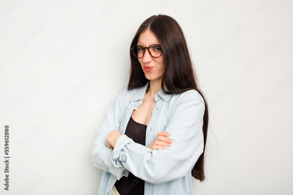 Young caucasian woman isolated on white background frowning face in displeasure, keeps arms folded.