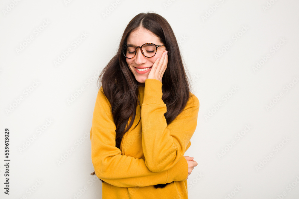 Young caucasian woman isolated on white background laughs happily and has fun keeping hands on stomach. Young caucasian woman isolated on white background laughs happily and has fun keeping hands on stomach.