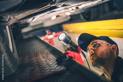 Mechanic Checking Car Undercarriage During Regular Vehicle Inspection