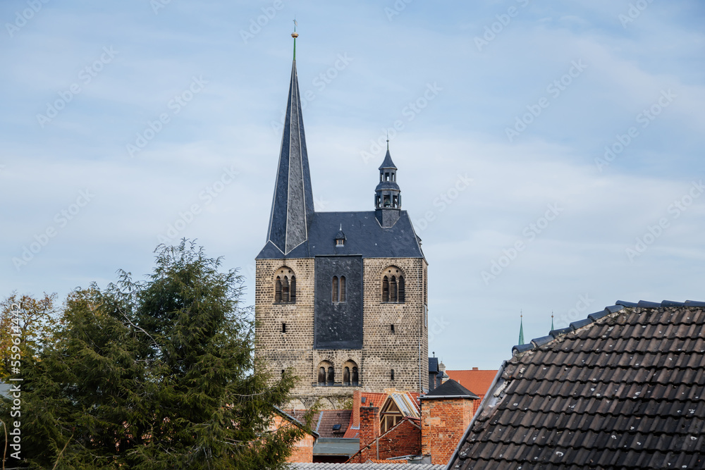 Fototapeta premium Quedlinburg, Saxony-Anhalt, Germany, 28 October 2022: Panoramic view of city from observation platform, old houses with red tiled roofs, tower and spire of St. Benedict church, sunny autumn day