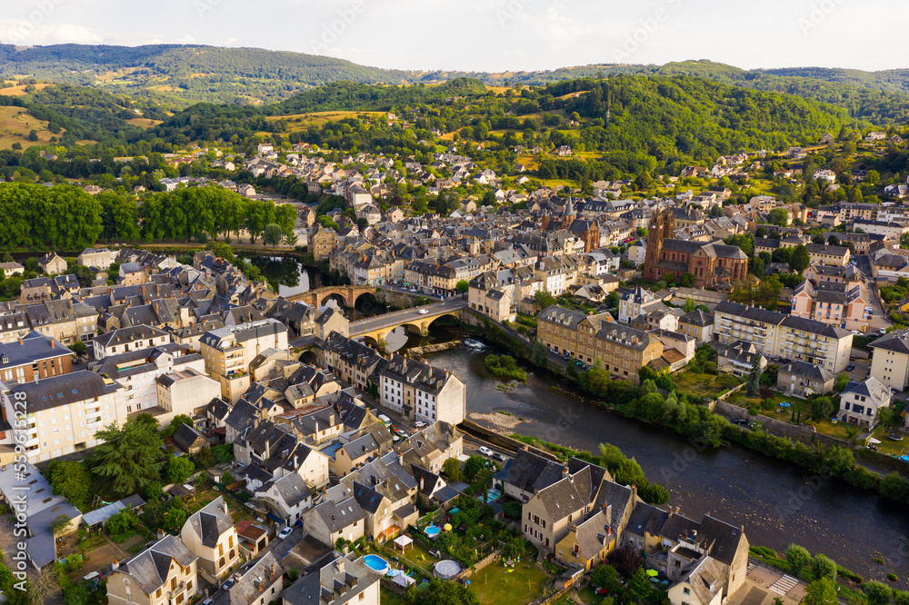 Picturesque drone view of summer cityscape of Espalion on Lot riverbanks overlooking Gothic building of Church of St. John Baptist, Occitanie, France