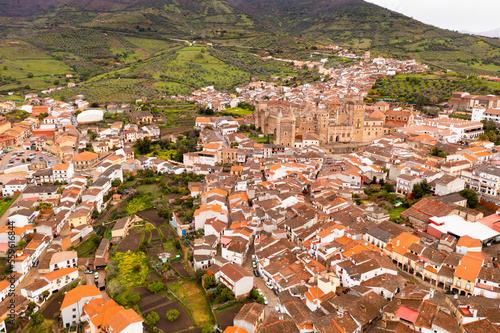 Scenic drone view of small Spanish town of Guadalupe in green valley of province of Caceres overlooking brownish roofs  photo