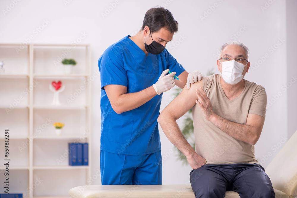 Obraz premium Old male patient visiting young male doctor in vaccination conce