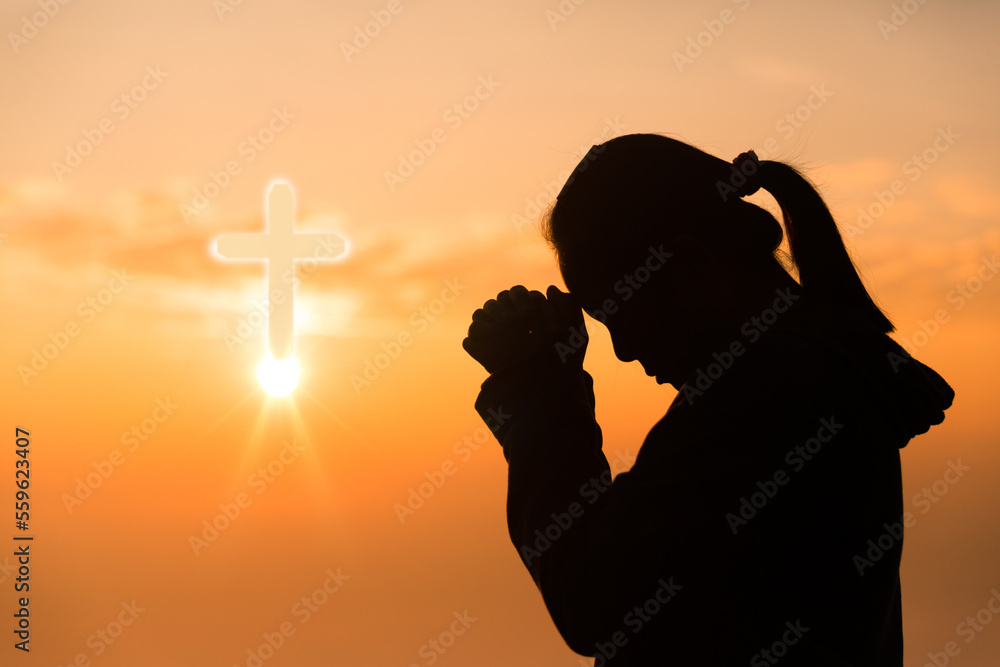 Faith of christian concept. Spiritual prayer hands over sun shine with  blurred beautiful sunset background. Female hands worship God with love and  faith. silhouette of a woman praying with a cross. Stock
