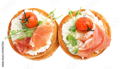 Tasty organic rusks with prosciutto, cream cheese and tomatoes on white background, top view