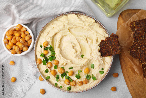 Fototapeta Naklejka Na Ścianę i Meble -  Delicious hummus with chickpeas and crispbread served on light grey table, flat lay