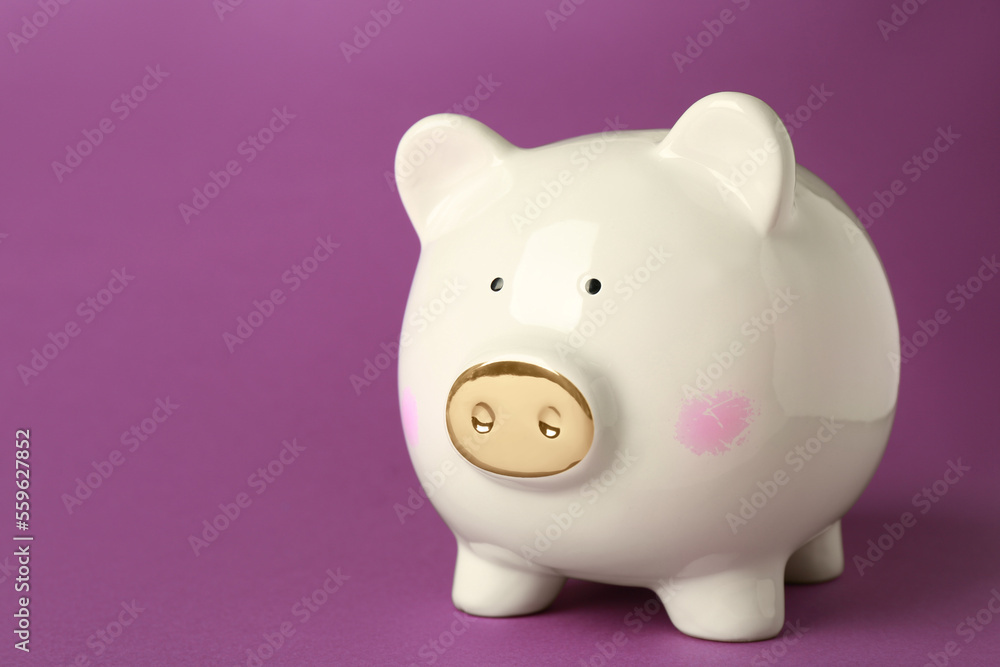 Ceramic piggy bank on purple background. Space for text Ceramic piggy bank on purple background. Space for text