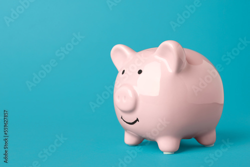 Ceramic piggy bank on turquoise background. Space for text
