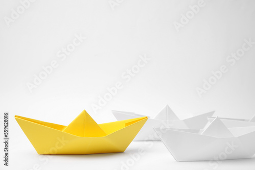 Group of paper boats following yellow one on white background. Leadership concept