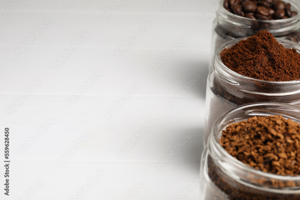 Jars with instant, ground coffee and roasted beans on white table, space for text Jars with instant, ground coffee and roasted beans on white table, space for text