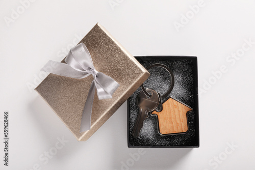 Fényképezés Key with trinket in shape of house and gift box on light grey background, flat lay
