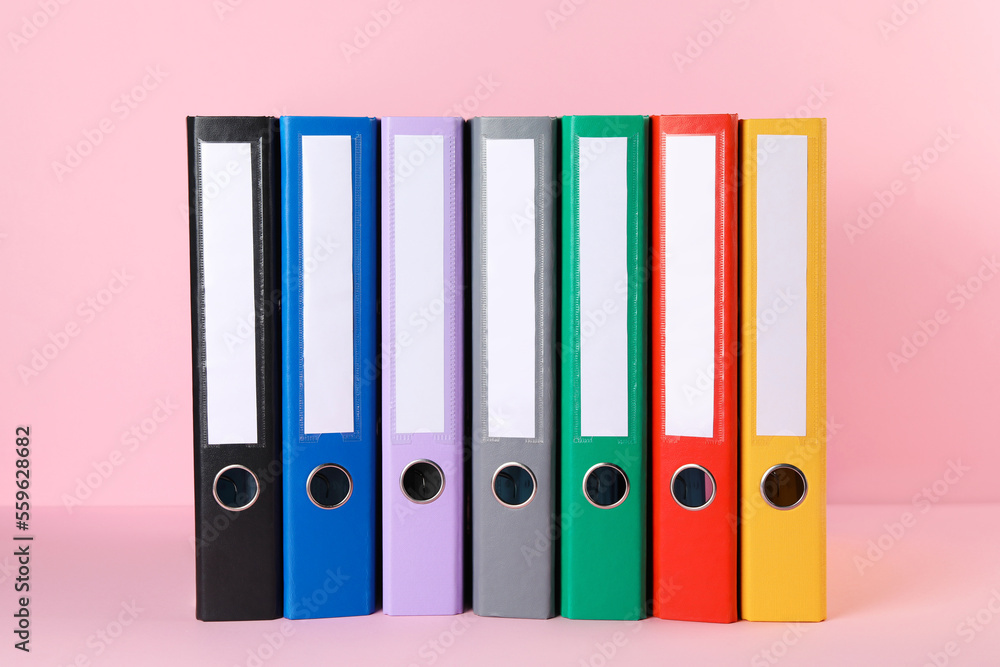 Many hardcover office folders on pink background Many hardcover office folders on pink background