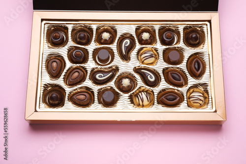 Box of delicious chocolate candies on pink background, closeup