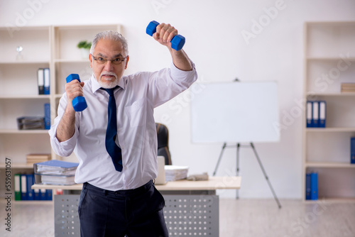 Old male employee doing sport exercises at workplace