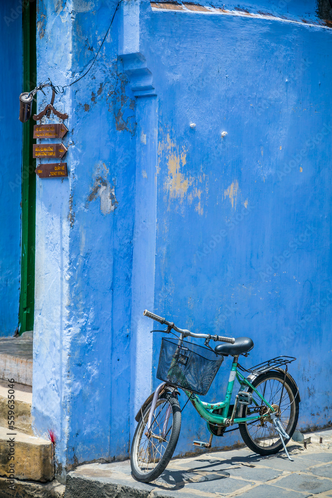 A bicycle with a basket leaning against a bright blue wall at Hoi An in Vietnam