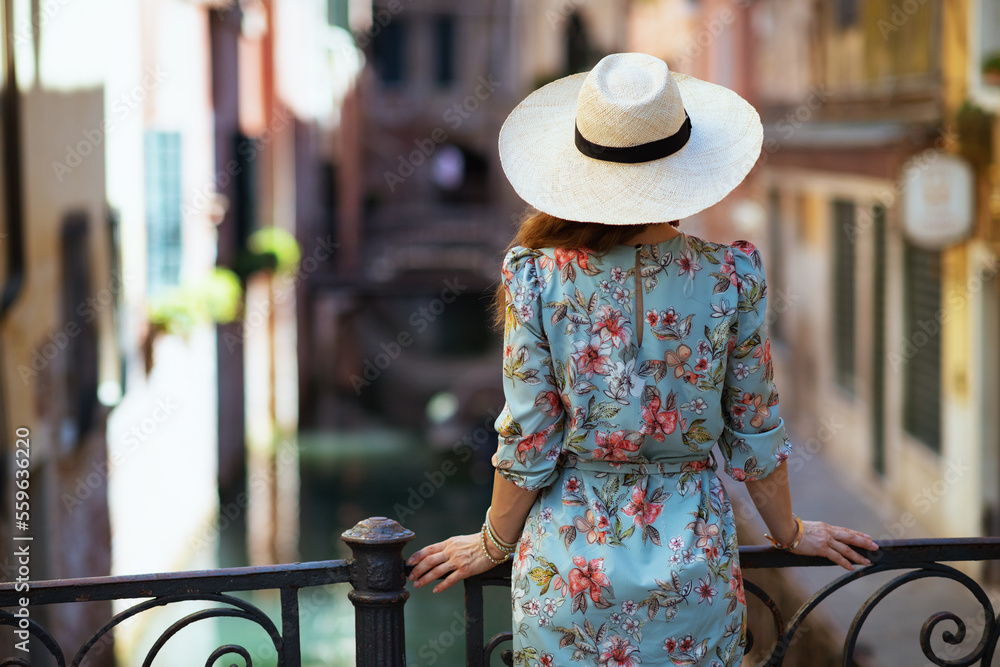 Seen from behind stylish traveller woman in floral dress