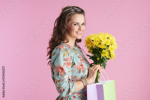Portrait of happy trendy woman in floral dress on pink