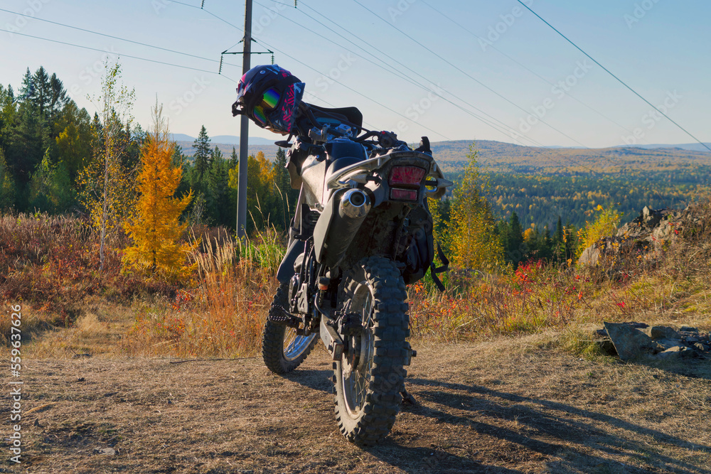 Naklejka premium A sports motorcycle stands against the backdrop of a mountainous area in autumn close-up.