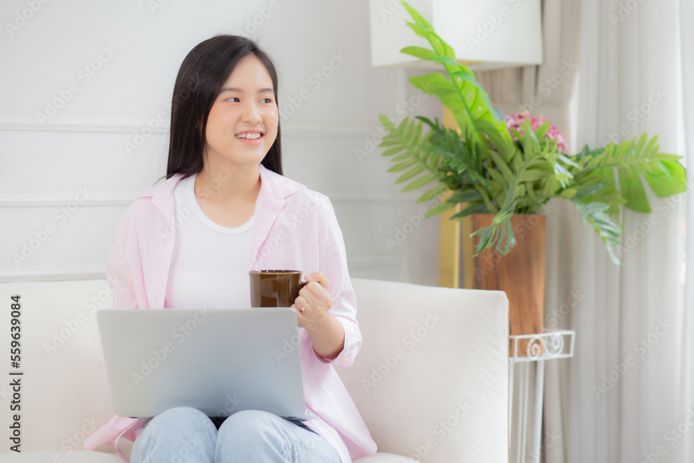 Young asian business woman work from home with laptop computer and drinking coffee on sofa in living room, freelance girl using notebook sitting on couch with comfort and relax, lifestyles concept. Young asian business woman work from home with laptop computer and drinking coffee on sofa in living room, freelance girl using notebook sitting on couch with comfort and relax, lifestyles concept.