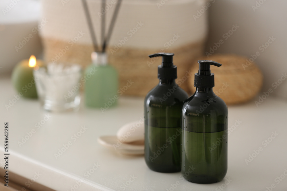 Green soap dispensers on white countertop in bathroom. Space for text