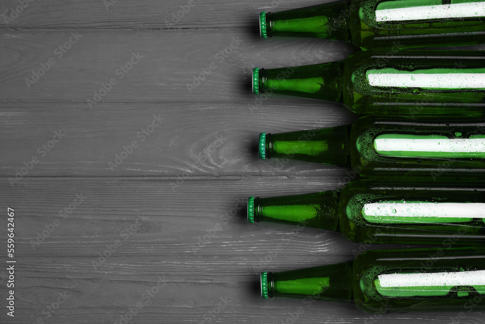 Glass bottles of beer on grey wooden background, flat lay. Space for text Glass bottles of beer on grey wooden background, flat lay. Space for text