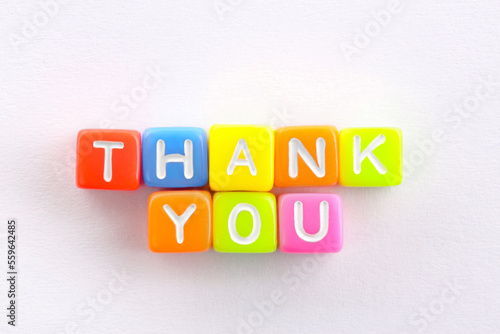 Phrase Thank You made of colorful cubes on white table, top view