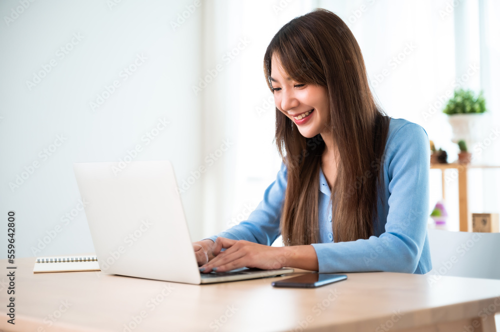 Young asian woman working at home. Female using computer laptop on desk at house Young asian woman working at home. Female using computer laptop on desk at house