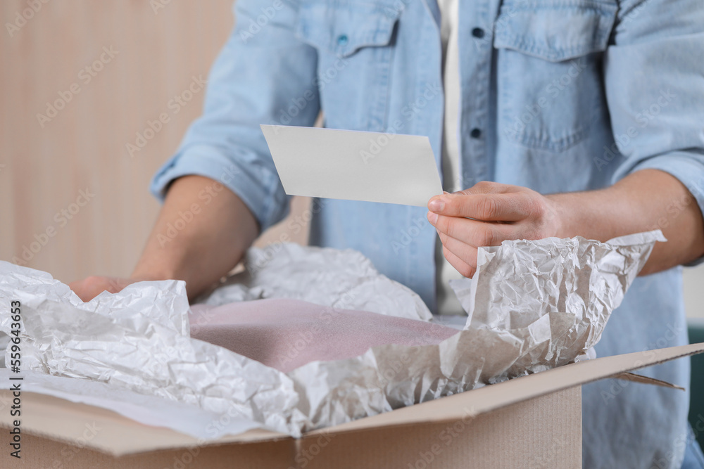Man holding greeting card near parcel with Christmas gift, closeup Man holding greeting card near parcel with Christmas gift, closeup