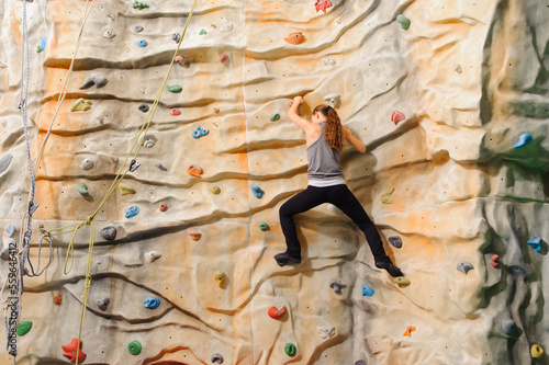 Woman climbing on man-made cliff in the sport centre