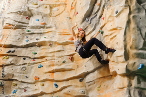 Woman climbing on man-made cliff in the sport centre