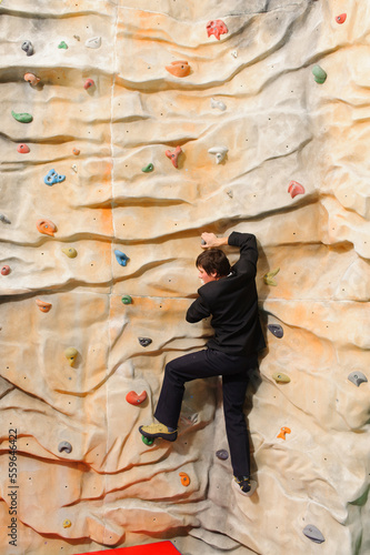 Businessman climbing on man-made cliff in the sport centre