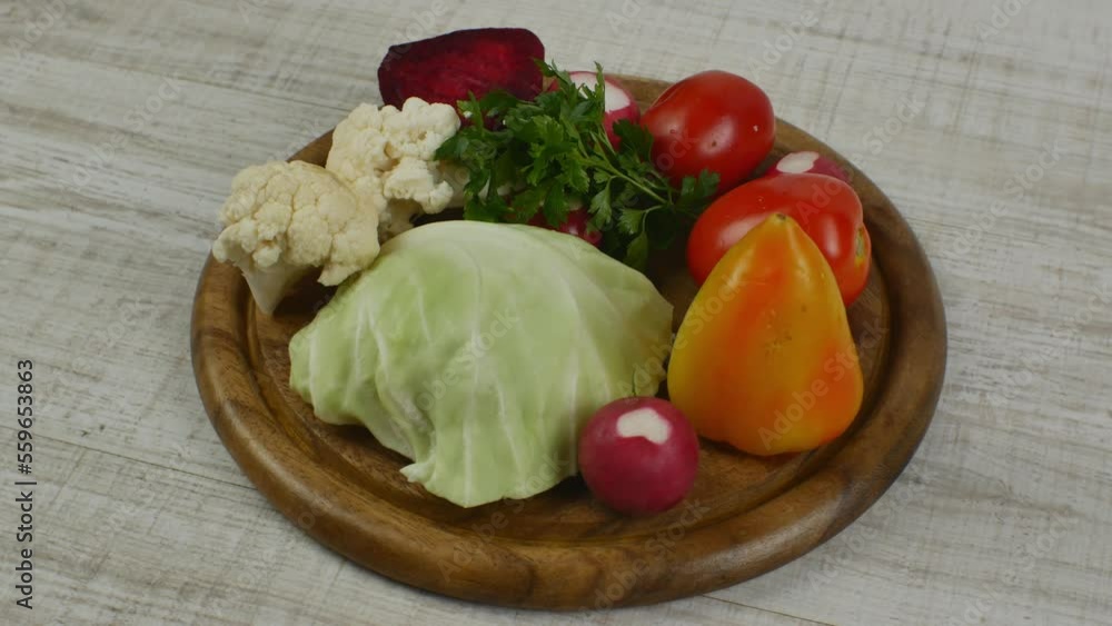Beautifully stacked fresh salad vegetables on a round brown wooden cutting board. Vegetarianism, veganism, raw food healthy lifestyle. Healthy eating and longevity Beautifully stacked fresh salad vegetables on a round brown wooden cutting board. Vegetarianism, veganism, raw food healthy lifestyle. Healthy eating and longevity