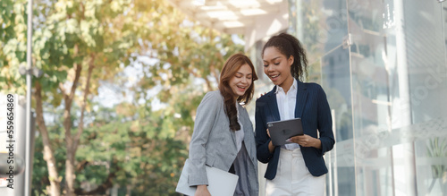 Fényképezés Two asia business women in conversation walking together on city street