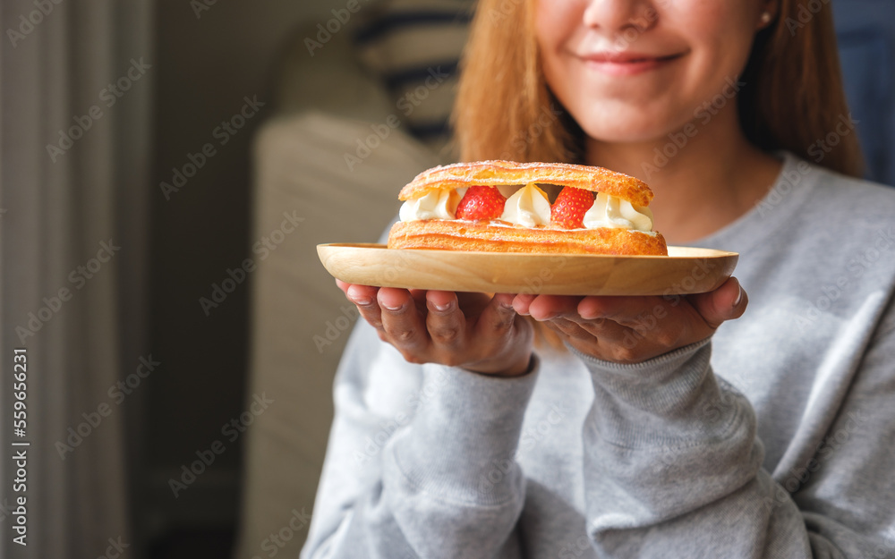 Closeup image of a woman holding a plate of strawberry Eclair Closeup image of a woman holding a plate of strawberry Eclair