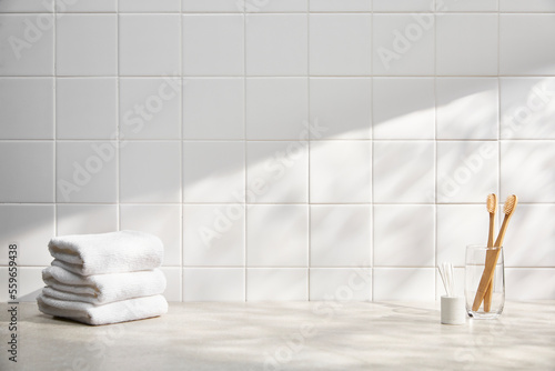 front view of bathroom with white tile wall  various bath objects  and sunlight. copy space.