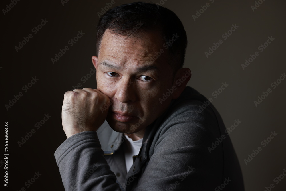 Middle-aged Japanese man in gray casual shirt on gray background. Conceptual image of world peace, stability in daily life, and sustainable living. Middle-aged Japanese man in gray casual shirt on gray background. Conceptual image of world peace, stability in daily life, and sustainable living.