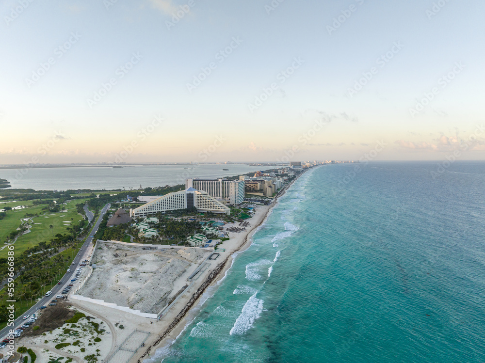 Aerial view of the beautiful tropical beach of Cancun, Mexico. Clear turquoise sea water, white sand and palm trees. Blue hour.