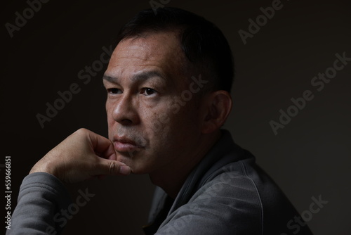 Middle-aged Japanese man in gray casual shirt on gray background. Conceptual image of world peace, stability in daily life, and sustainable living.