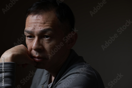 Middle-aged Japanese man in gray casual shirt on gray background. Conceptual image of world peace, stability in daily life, and sustainable living.