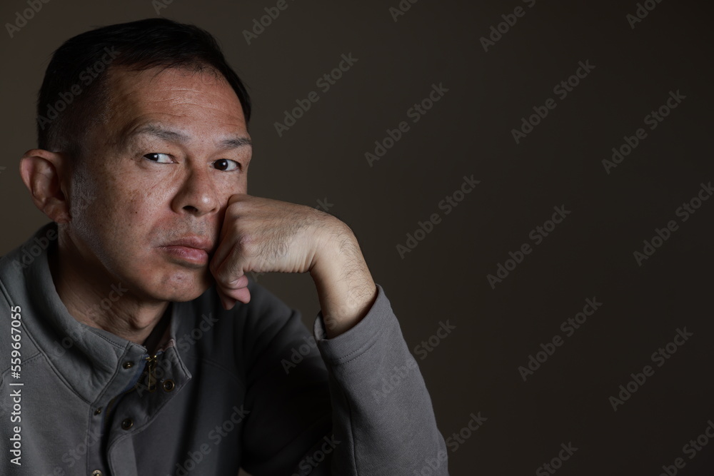 Middle-aged Japanese man in gray casual shirt on gray background. Conceptual image of world peace, stability in daily life, and sustainable living. Middle-aged Japanese man in gray casual shirt on gray background. Conceptual image of world peace, stability in daily life, and sustainable living.