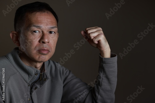 Middle-aged Japanese man in gray casual shirt on gray background. Conceptual image of world peace, stability in daily life, and sustainable living. © DRN Studio