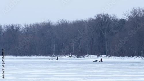 Wide shot of people ice fishing on a frozen bay. photo