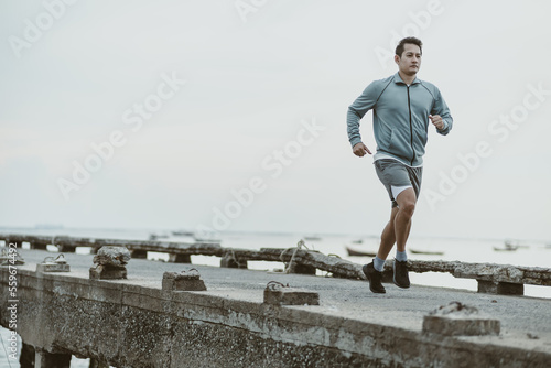healthy lifestyle young fitness man running at seaside old bridge. Outdoor workout, Healthy lifestyle concept.