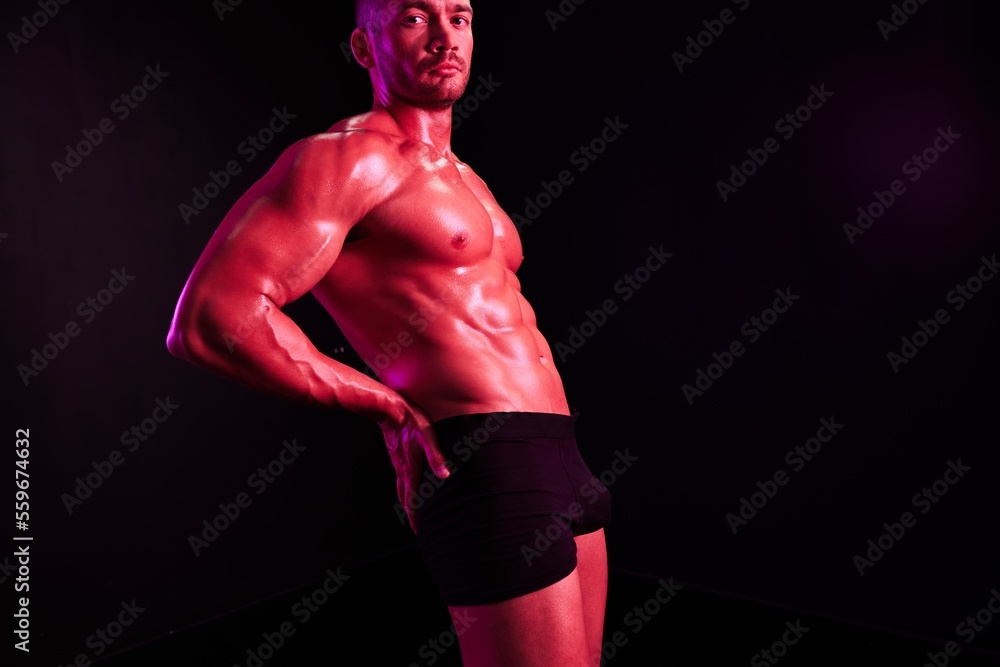Man professional athlete with naked torso in sports uniform, isolated on multicolored background in neon light. Advertising, sports, active lifestyle, competition, challenge concept. 