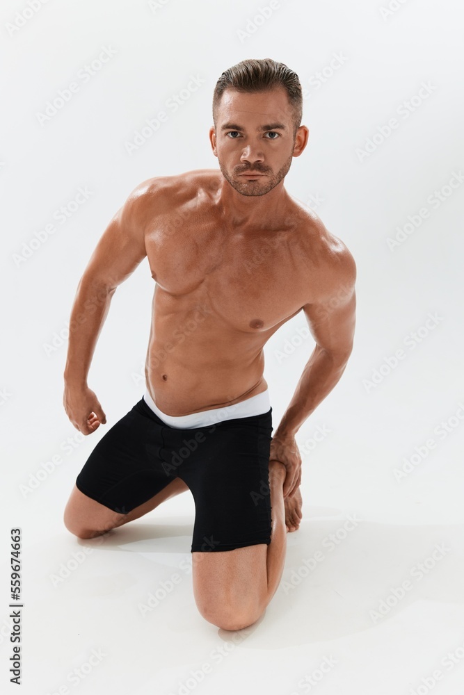 Man athletic body bodybuilder in briefs with naked torso abs full-length in the background, fitness classes. Advertising, sports, active lifestyle, competition, challenge concept.