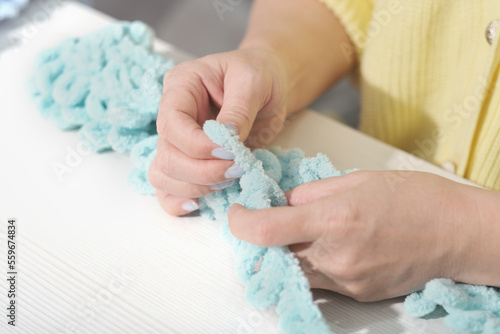 finger knit concept. new way to knit accessories using no needles. hand made knitting. female hands with soft yarn.