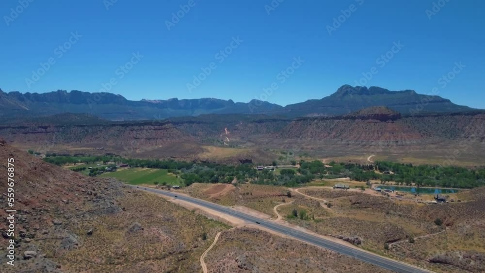 Drone shot of road running through Mount Zion with a mountain range in the background located in Southern Utah Drone shot of road running through Mount Zion with a mountain range in the background located in Southern Utah