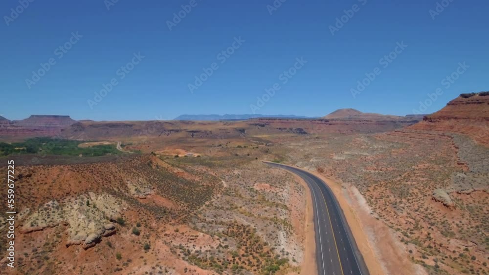 Ascending drone shot of Long road running through Mount Zion with mountain range in the background located in Southern Utah