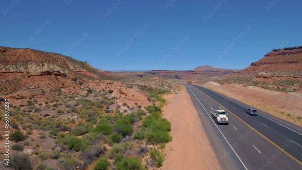 Ascending drone shot starting from ground level to 200 feet up of a car and truck driving down a road running through Mount Zion with Mountain range in the background located in Southern Utah Ascending drone shot starting from ground level to 200 feet up of a car and truck driving down a road running through Mount Zion with Mountain range in the background located in Southern Utah